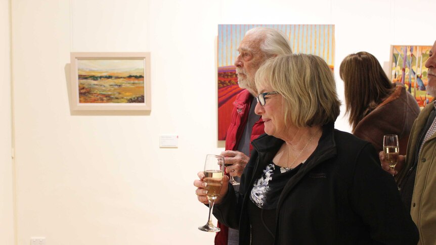 Broken Hill councillor Maureen Clark smiles at a painting at the Pro Hart Outback Art Prize exhibition.