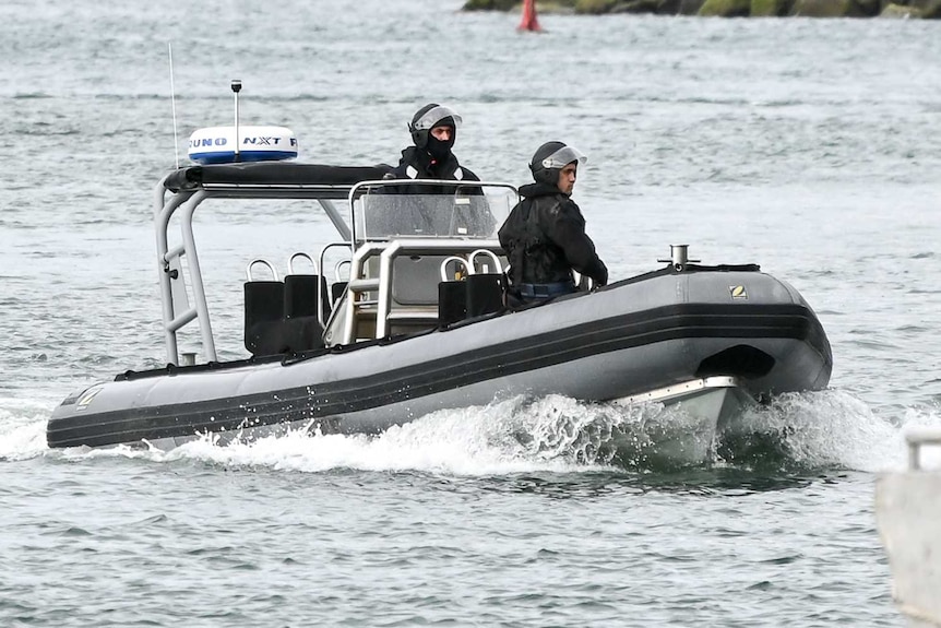 Two men in tactical gear on board a boat