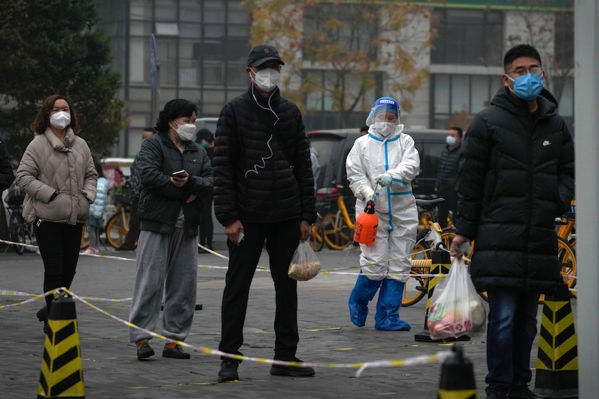 Des gens font la queue alors qu'une personne en matières dangereuses les pulvérise