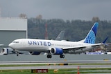 A wide shot of a Boeing 737 Max 9 airliner with United Airlines branding landing at an airport