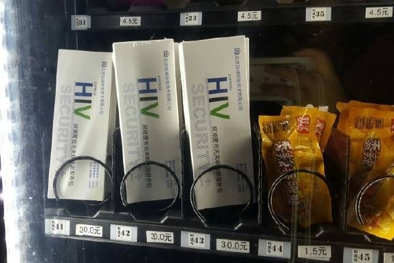 HIV kits sit next to sausage snacks in a vending machine.