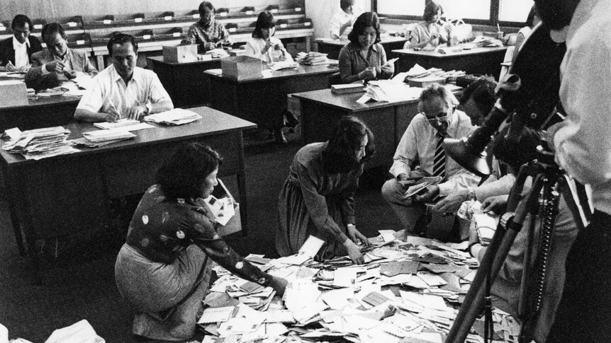 Radio Australia receives its weekly mail in 1969. Envelopes are all over the mail room floor, and staff appear very busy.