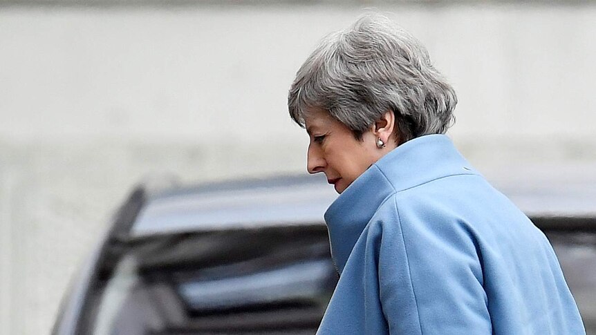 A close up shot of Theresa May looking down as she walks past a car on her way to 10 Downing Street