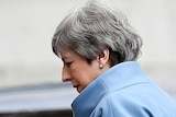 A close up shot of Theresa May looking down as she walks past a car on her way to 10 Downing Street