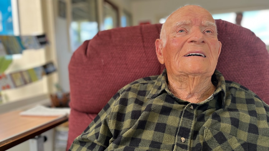 An elderly man sits in a chair.