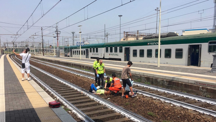 A man takes a selfie in front of a woman injured in a train accident in Italy.