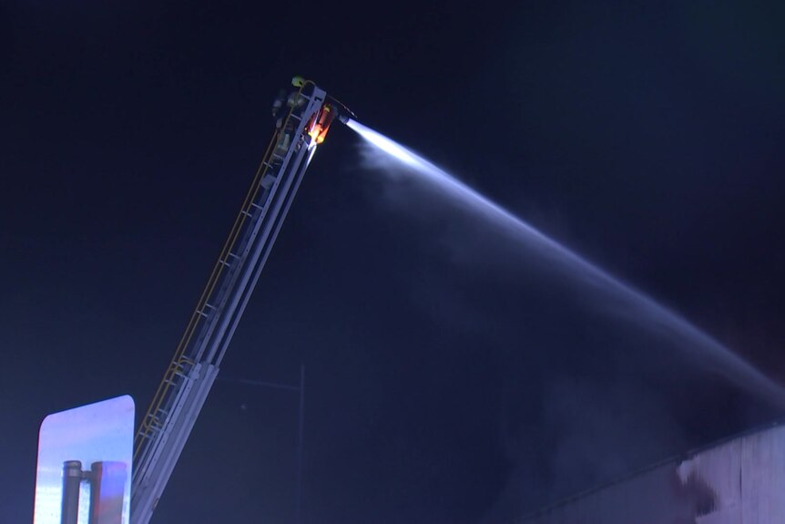 A crane used to pump water onto a fire at night.