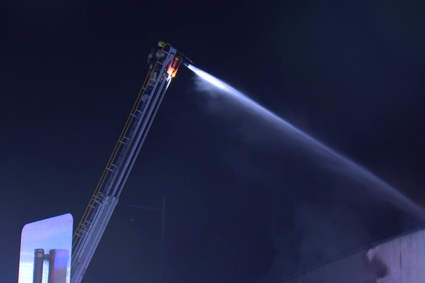 A crane used to pump water onto a fire at night.