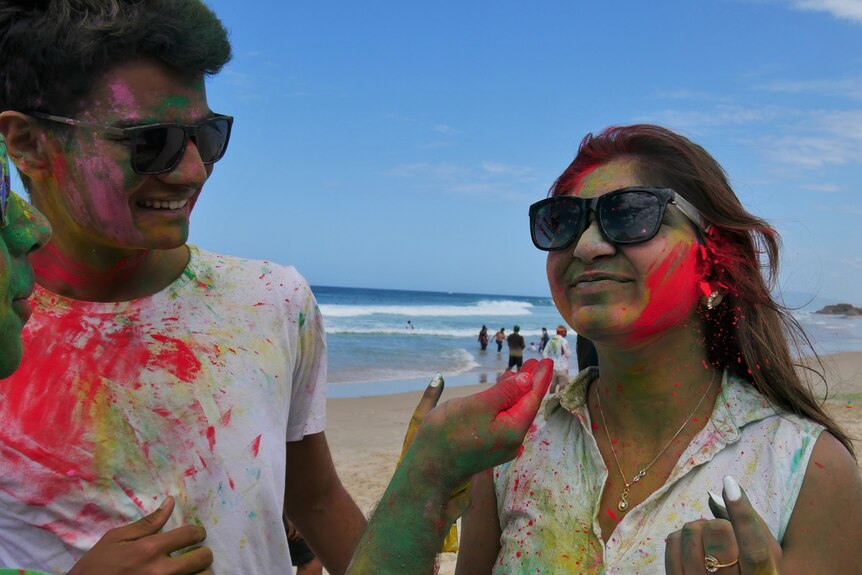 A young man and woman smile while having face coloured with traditional Indian colours