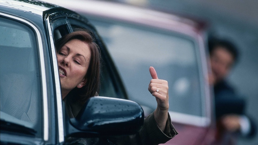 A woman in a car gestures to the motorist behind her.