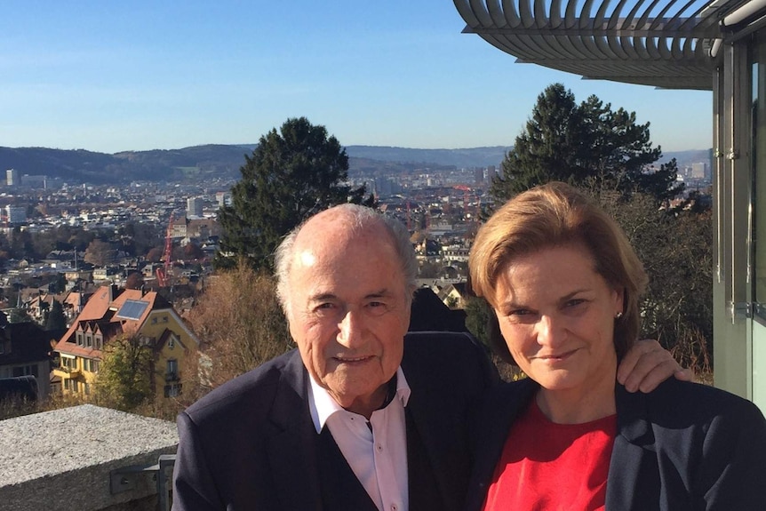 Sepp Blatter and Bonita Mersiades pose on a balcony overlooking a valley in the background