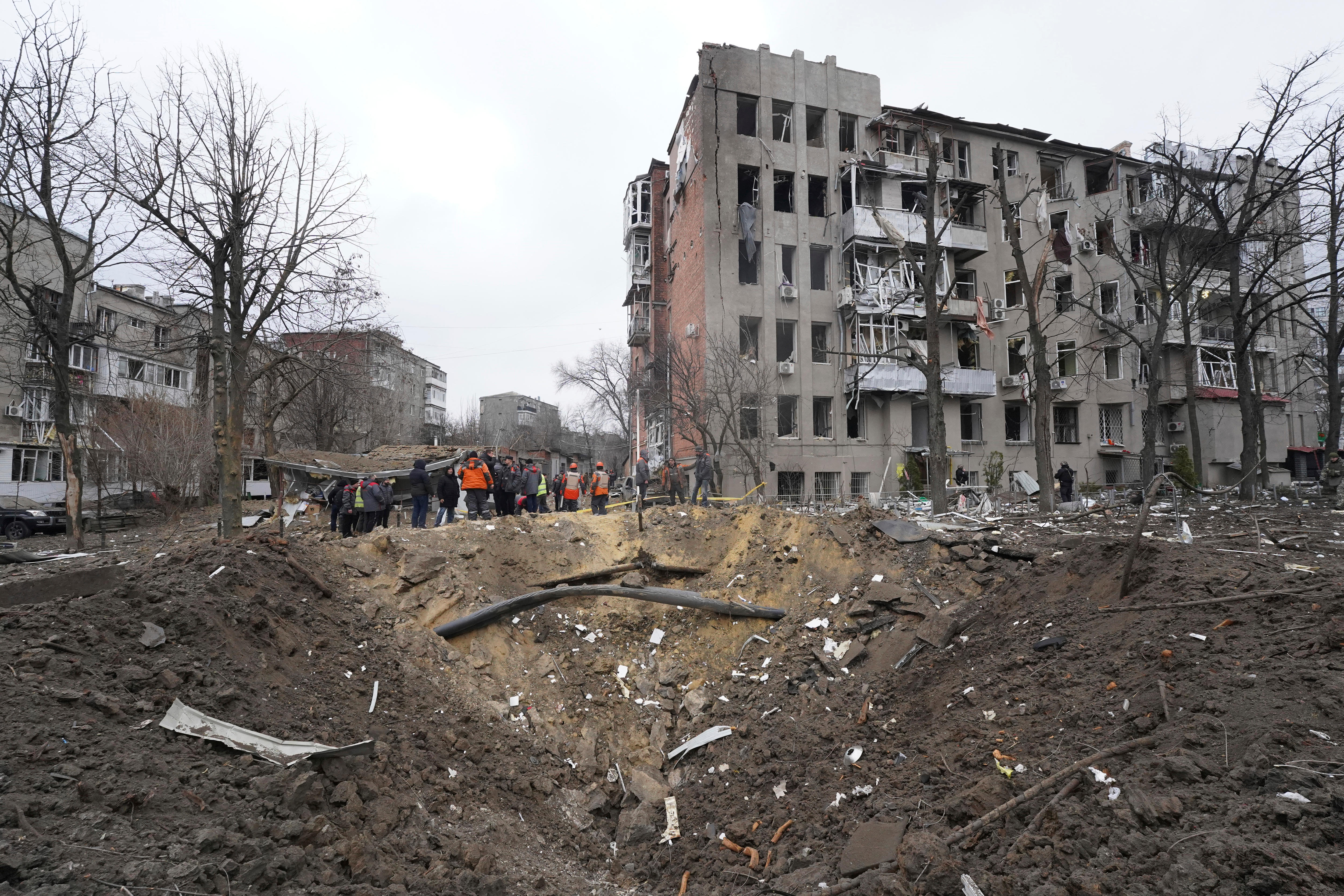 People stand near rubble and debris after a missile damaged an area of Kharkiv, Ukraine