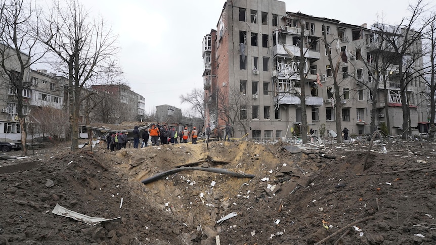 People stand near rubble and debris after a missile damaged an area of Kharkiv, Ukraine