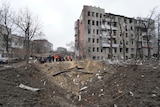 People stand near rubble and debris after a missile damaged an area of Kharkiv, Ukraine