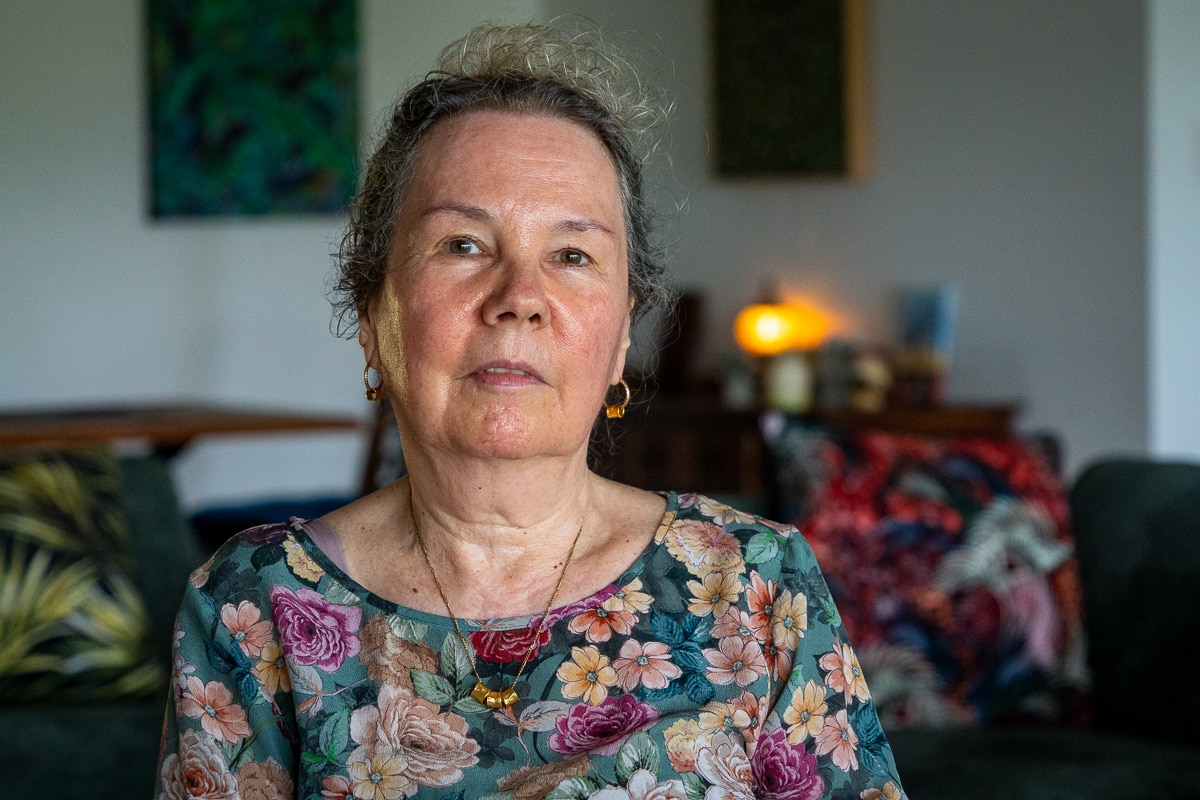 A woman wearing a green floral shirt looking directly into the camera.