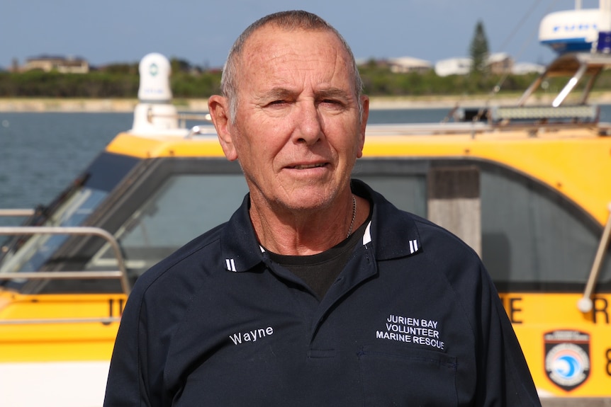 A head and shoulders shot of a man standing in front of a rescue boat.