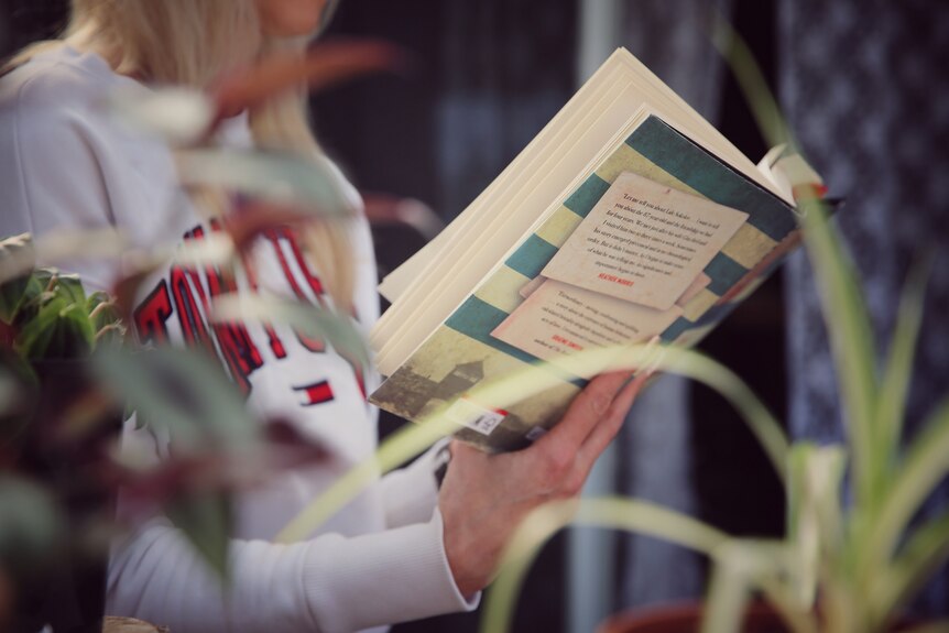 A blurred image of a woman reading a book.