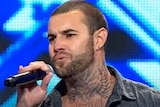 A tattooed man singing on stage