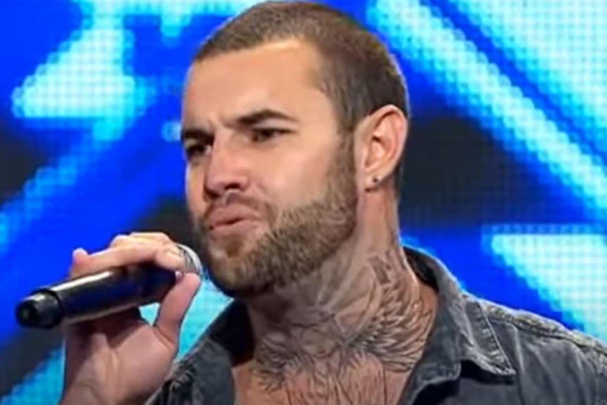 A tattooed man singing on stage