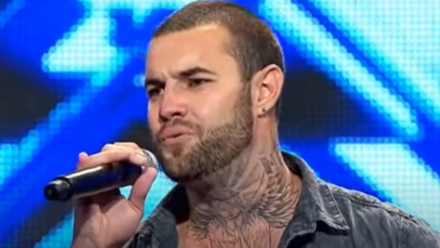 A tattooed man singing on stage