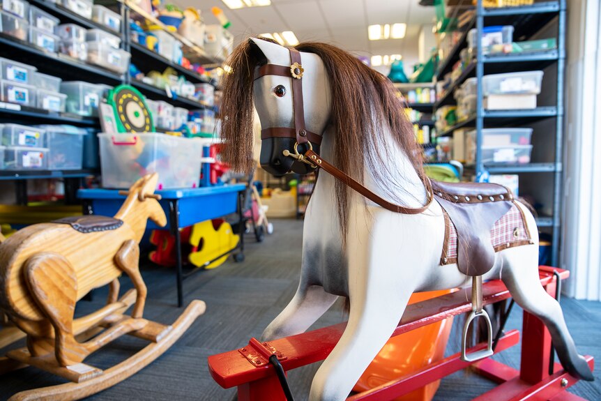 A rocking horse and rocking kangaroo sit among toys in a room.