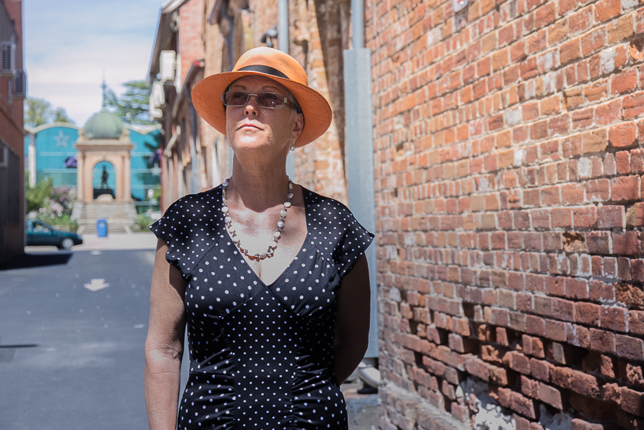 A woman wearing a hat standing in a laneway of old bricks