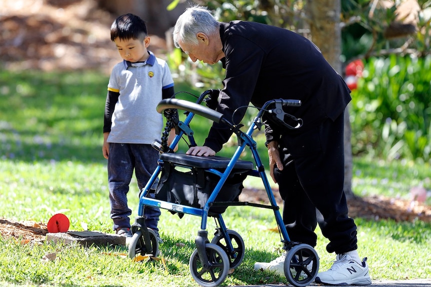 A young child stands next to an elderly man holding onto a walker on the ABC TV series Old People's Home For 4 Year Olds.
