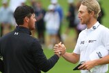 Mito Pereira and Will Zalatoris shake hands while looking at each other on the green