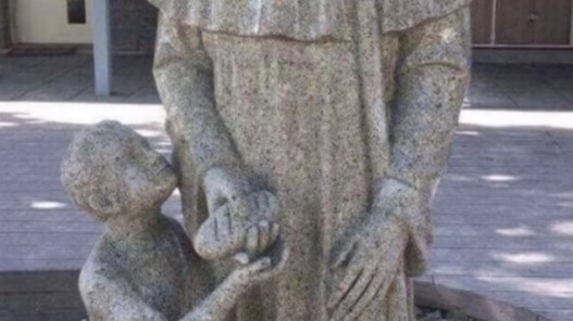A statue of a saint handing a child bread.