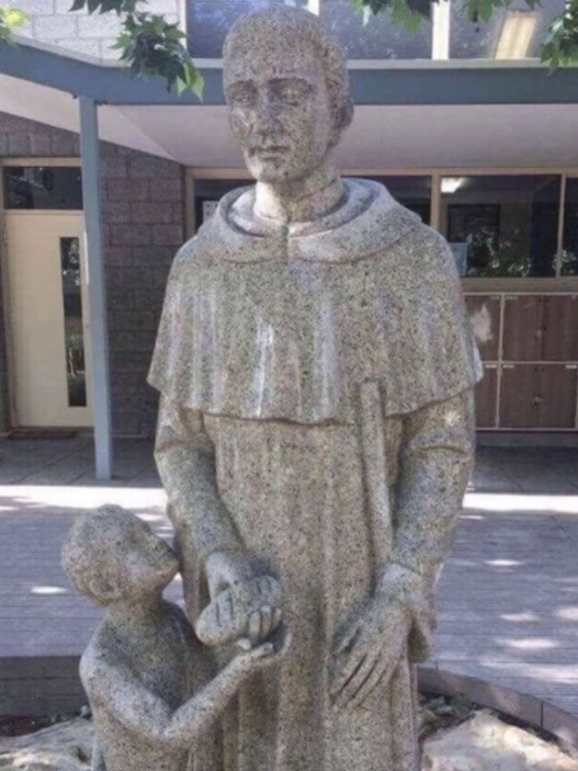A statue of a saint handing a child bread.