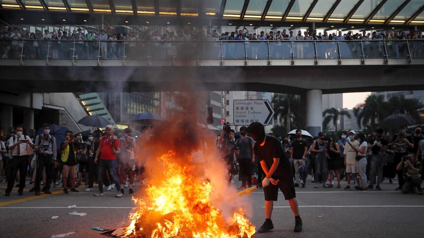People watch a protester burn a China 70th anniversary banner in Hong Kong.