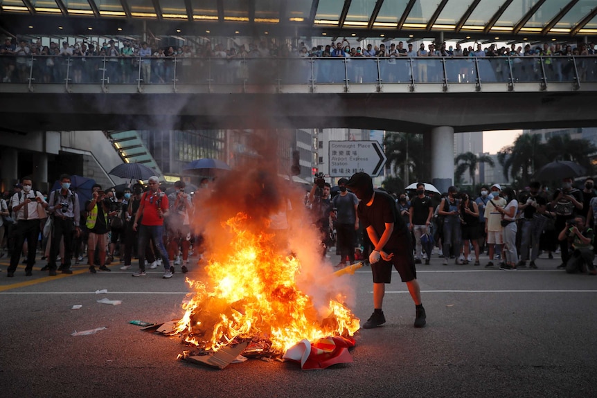 People watch a protester burn a China 70th anniversary banner in Hong Kong.