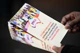 hands hold colourful leaflets that read Yes 23