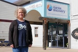 A woman stands in front of the Marine Discovery Centre, wearing a black cardigan