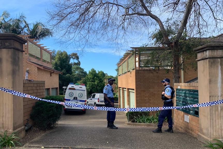 Two police and two vans in a driveway with police tape in front of it.