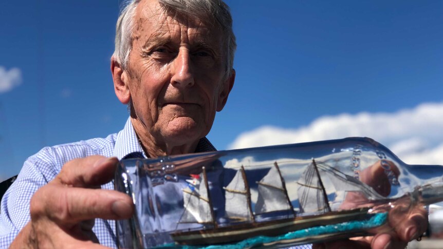 Michael Stoddart holds one of his ships-in-a-bottle outside