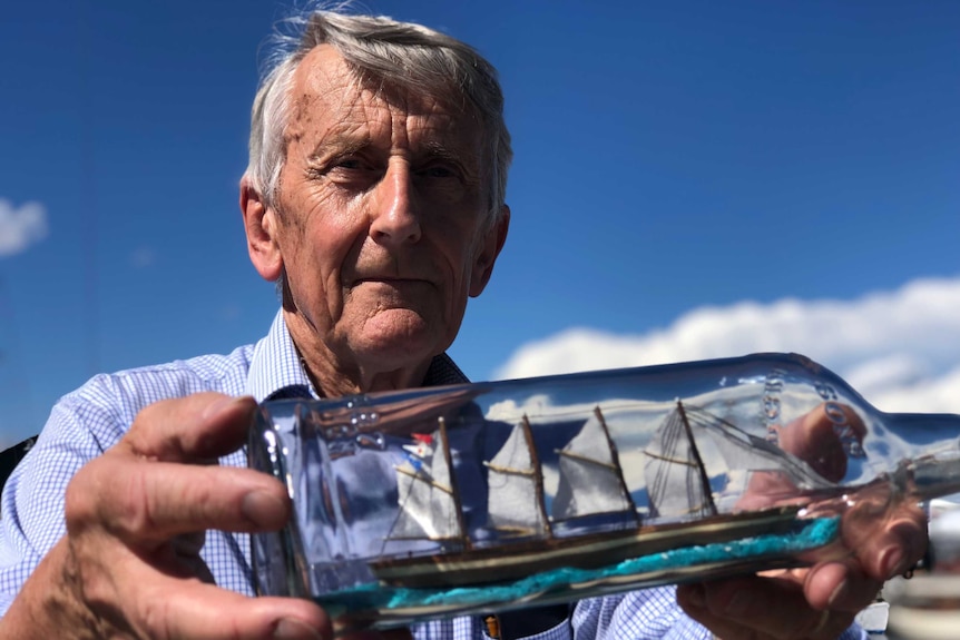 Michael Stoddart holds one of his ships-in-a-bottle outside