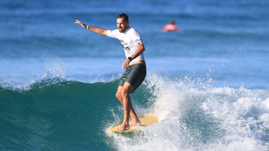 Bearded man rides a surfboard