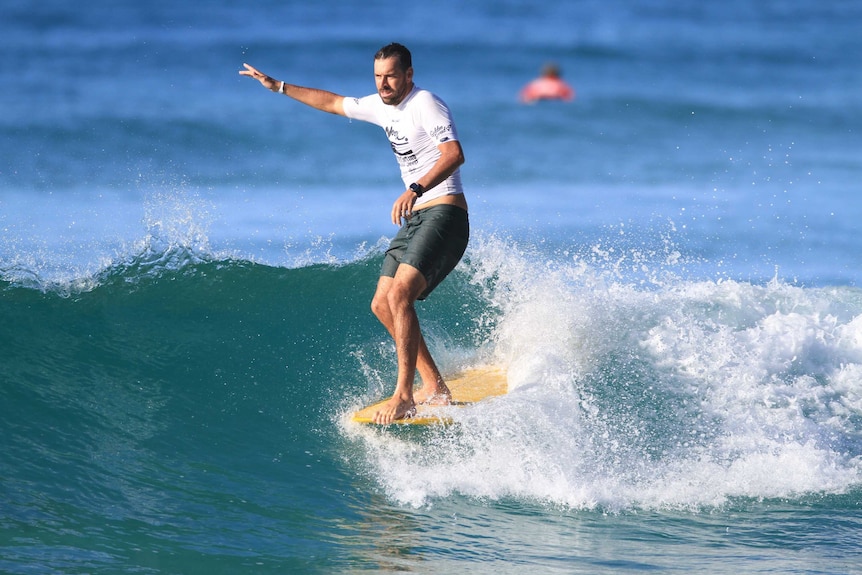 Bearded man rides a surfboard