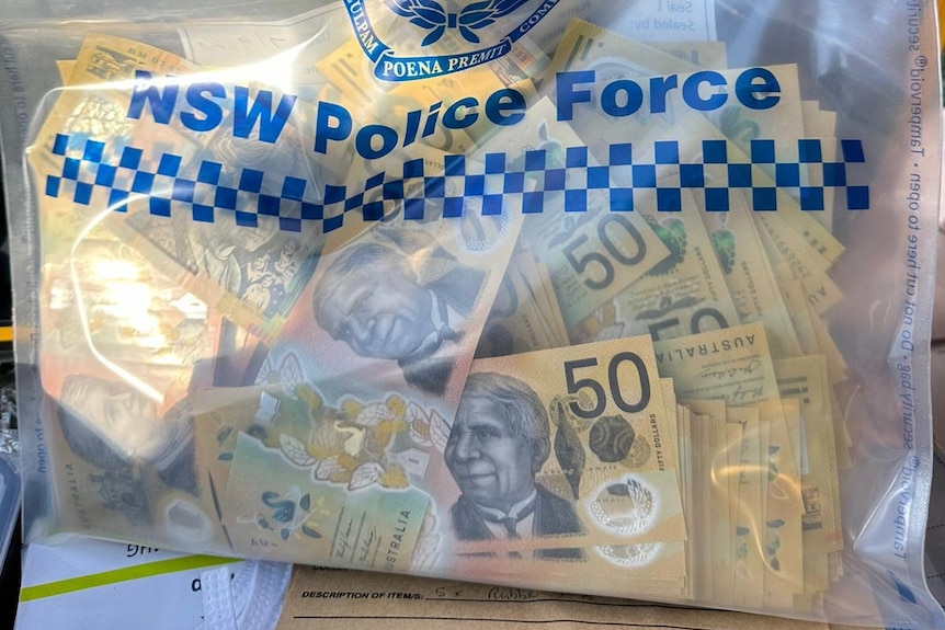 a bag from new south wales police with a bunch of fifty dollar notes inside it