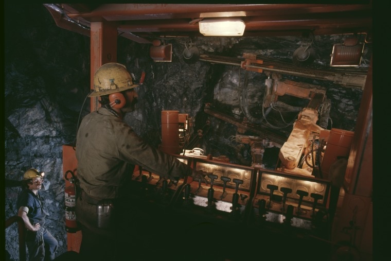 Two miner workers underground in the dark.