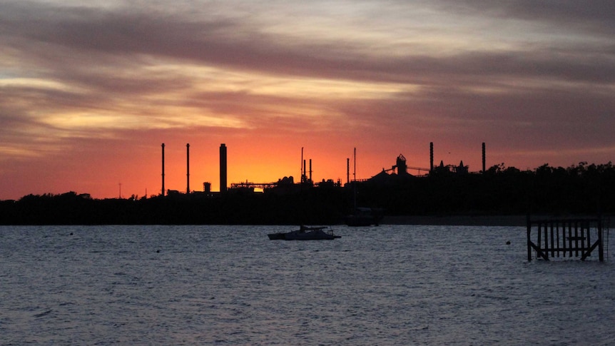 A sunset over a bay looking at an industrial area.