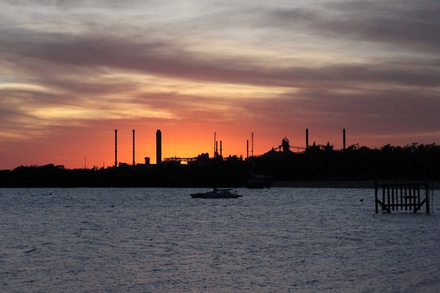 A sunset over a bay looking at an industrial area.