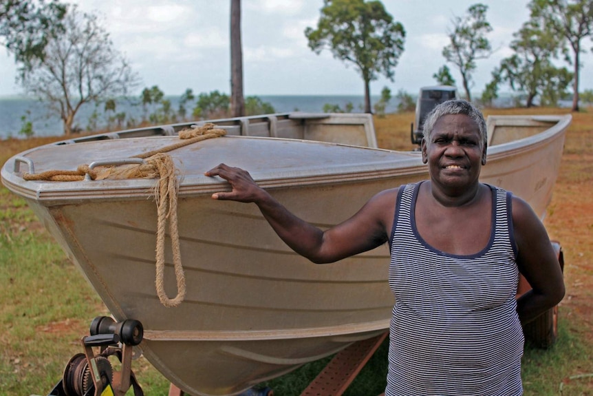 a woman standing next to an aluminium boat.