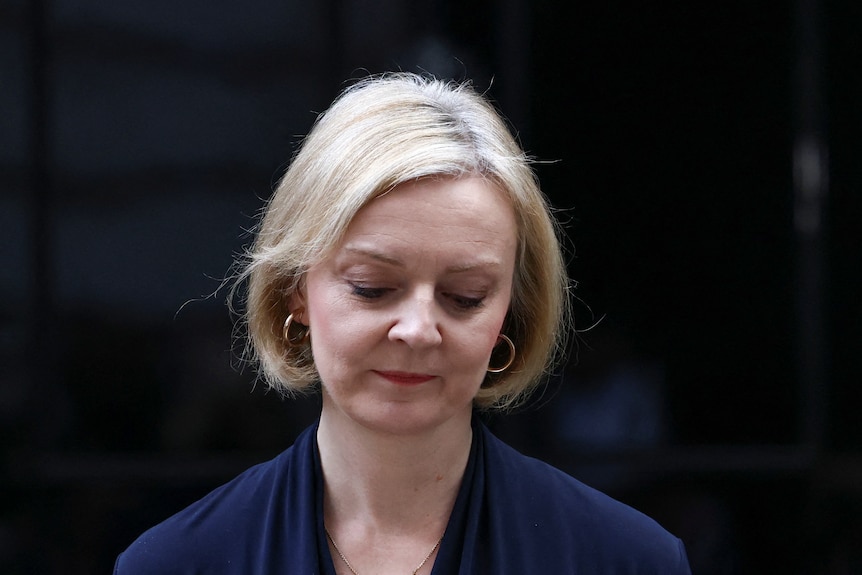 Liz Truss looks down as she delivers a speech in front of the black door of No 10.