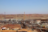 A photo of lots a giant equipment plant in the Pilbara, red dirt in front and behind it, blue sky above it.