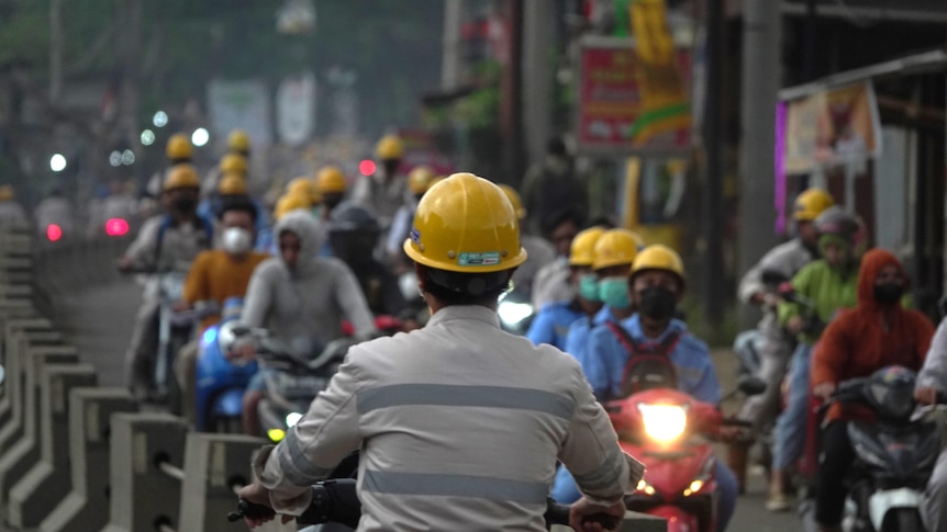 Workers wearing hard helmets drive to work.