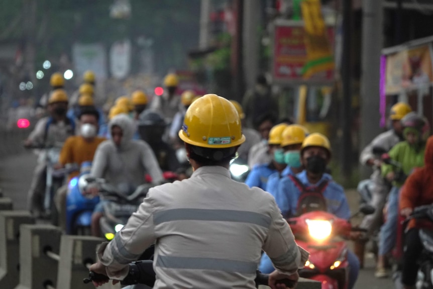 Workers wearing hard helmets drive to work.