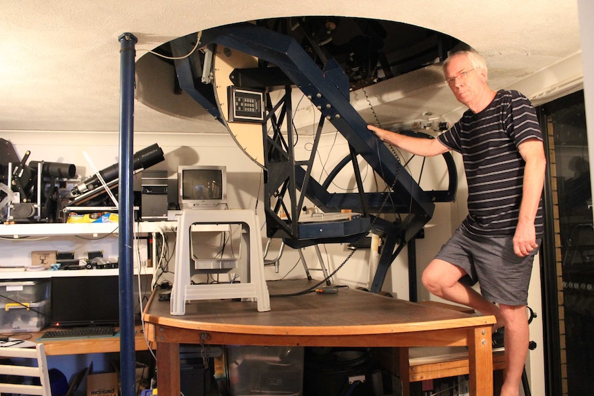 John Broughton stands under his homemade telescope, built into a dome on the side of his house in Reedy Creek, Queensland.