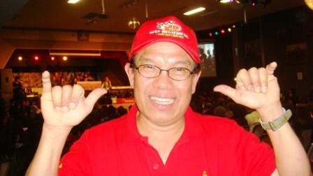Thai activist Somsak Rachso wearing red and smiling at the camera.